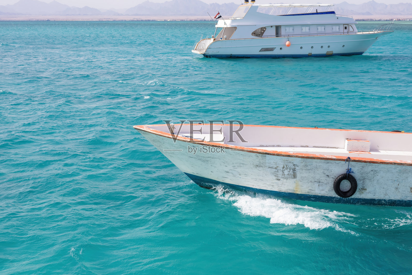 宁静海景中，白色小船漂浮在碧蓝的海水上，展现出田园诗般的海岸风光。照片摄影图片