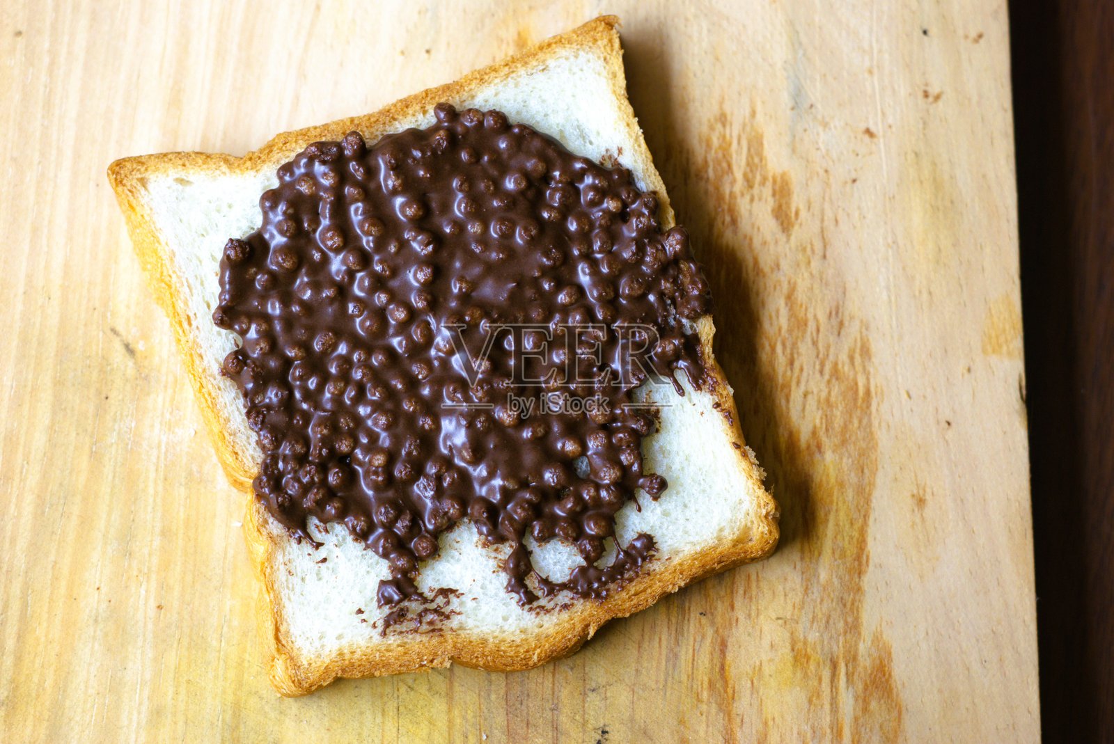 一片涂有巧克力酱的面包放在木板上照片摄影图片