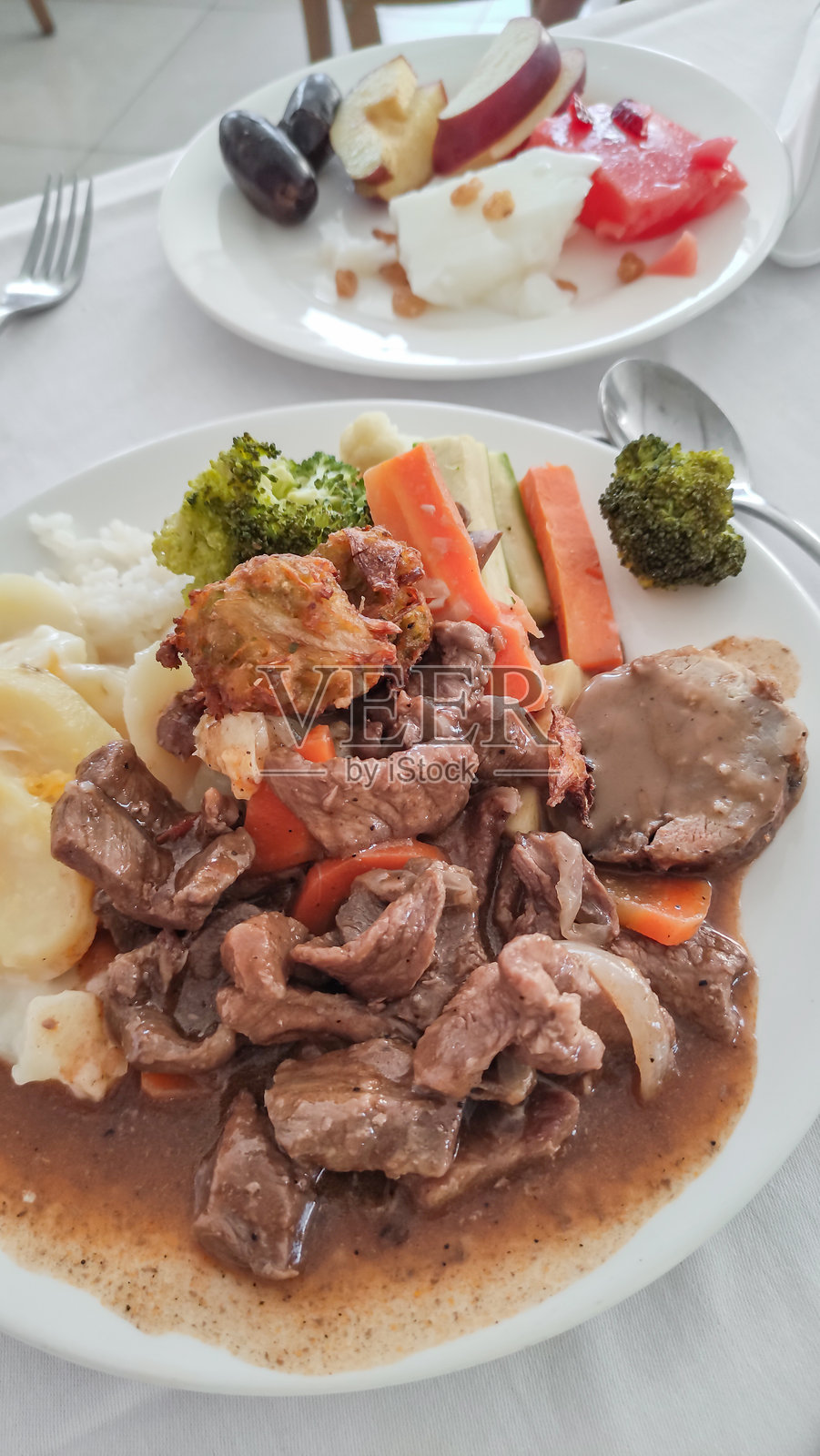 埃及萨塔亚度假村的牛肉炖菜配土豆泥、蔬菜和炸饺子，旁边还有水果沙拉照片摄影图片