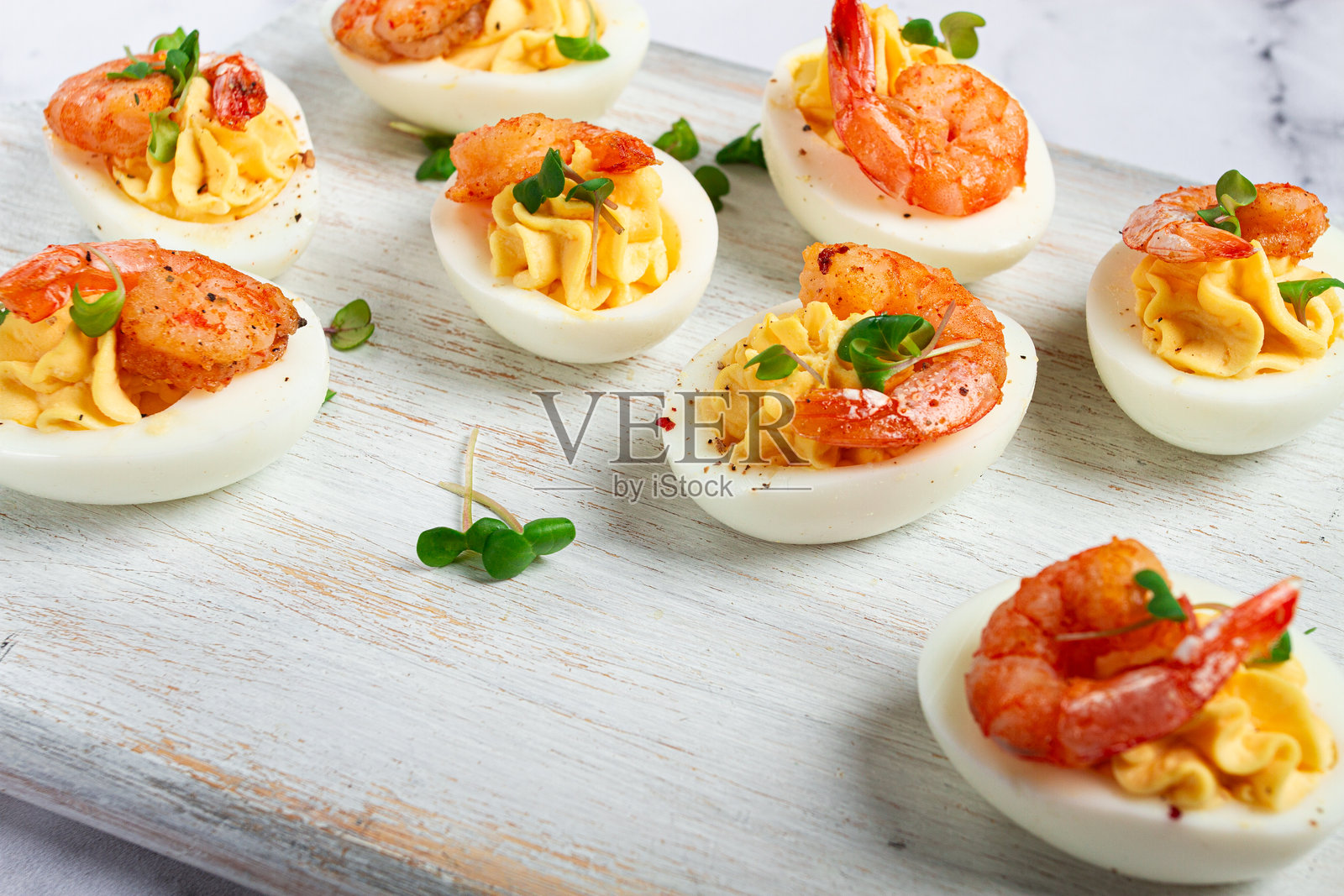 用蛋黄和蛋黄酱调味的煮鸡蛋，虾仁填充的鸡蛋，放在白色木质切菜板上，特写，聚焦，背景无人物。照片摄影图片