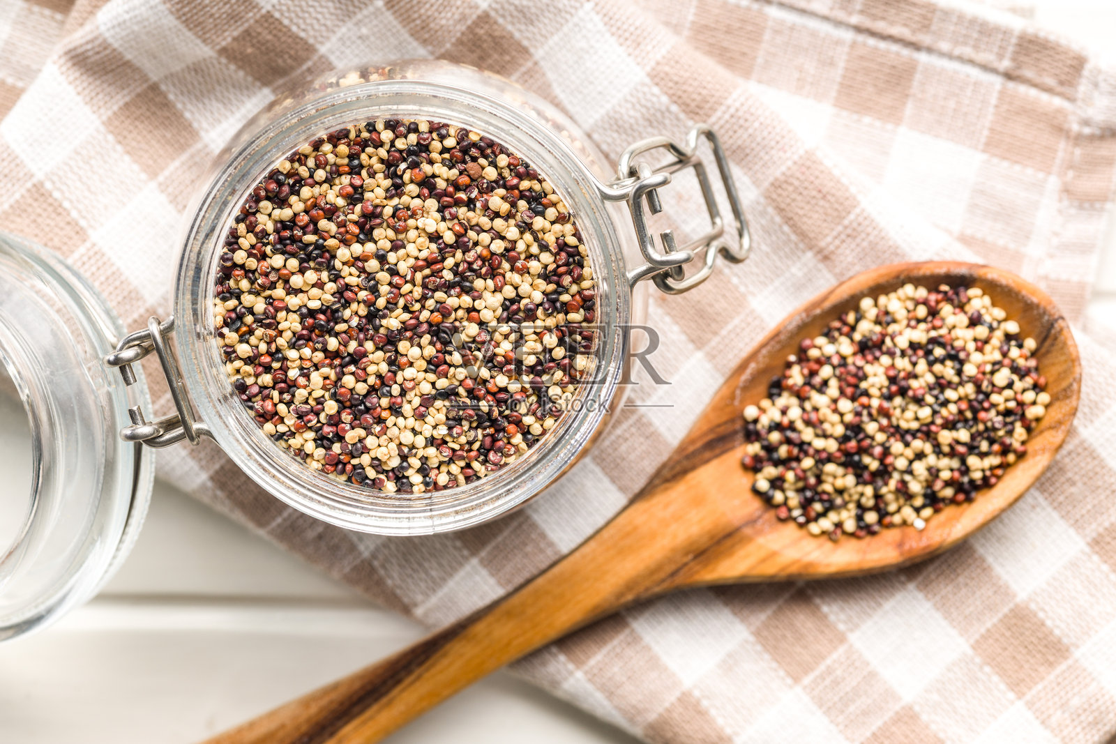 混合生藜麦种子装在罐子里，放在格子餐巾上。俯视图。照片摄影图片