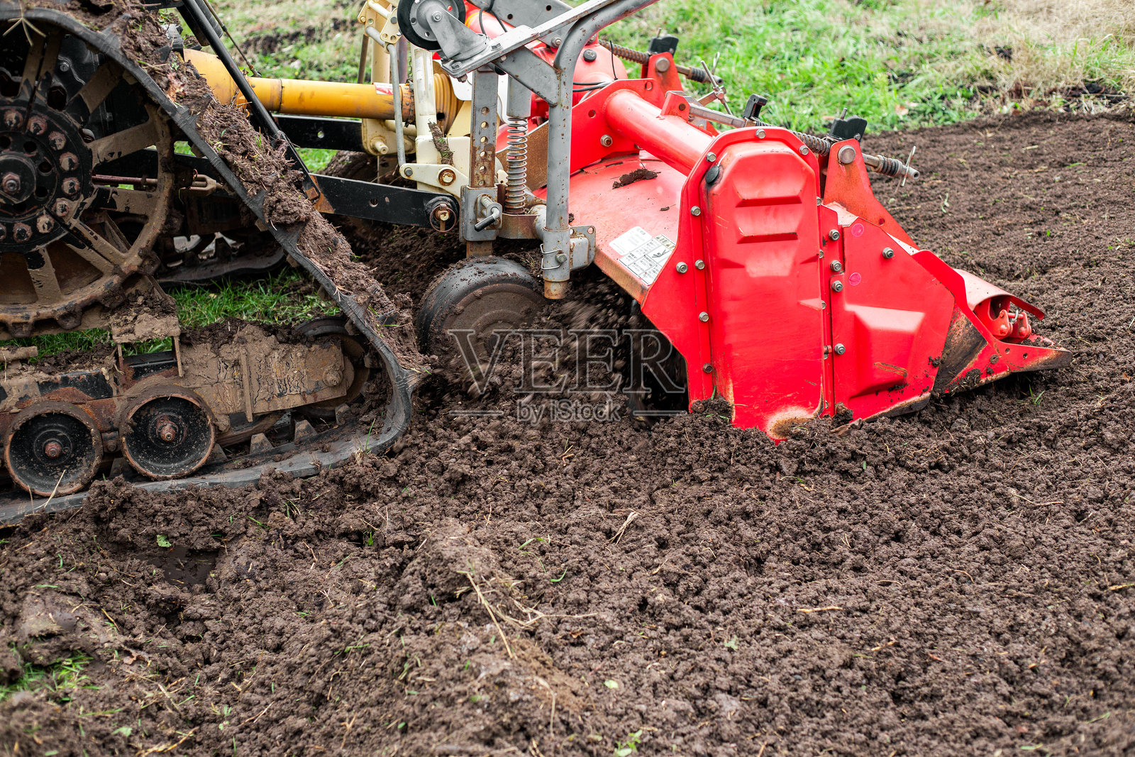 履带式拖拉机配备耕作切割机在菜园中松土照片摄影图片