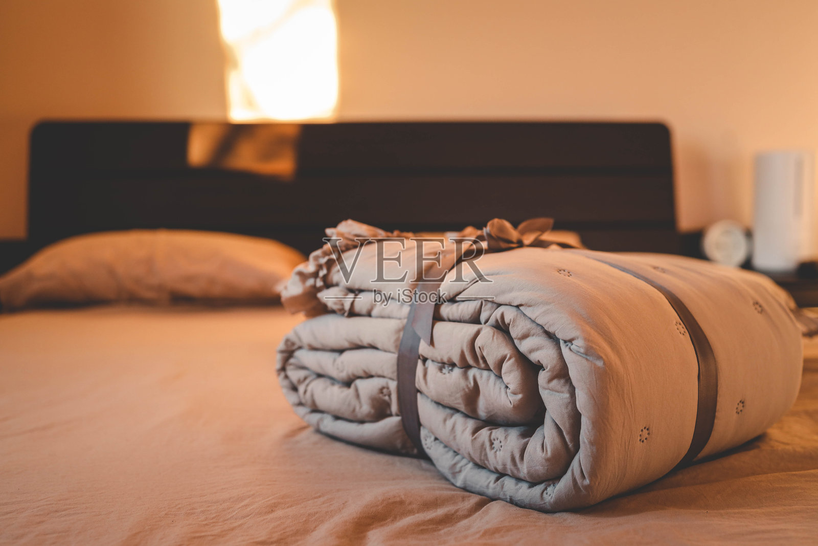 柔和米色的床上用品套件，带有褶边细节，用灰色丝带系在相配的米色背景上。完美适合舒适、优雅和简约家居装饰的主题。照片摄影图片