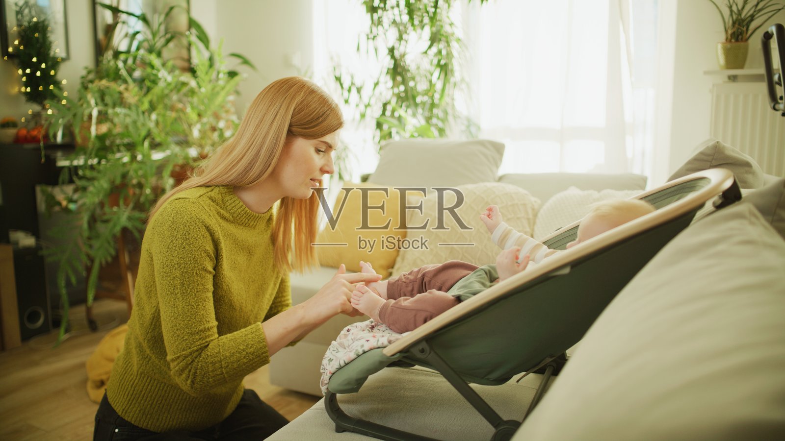 红发母亲在家中为宝宝按摩脚丫。照片摄影图片