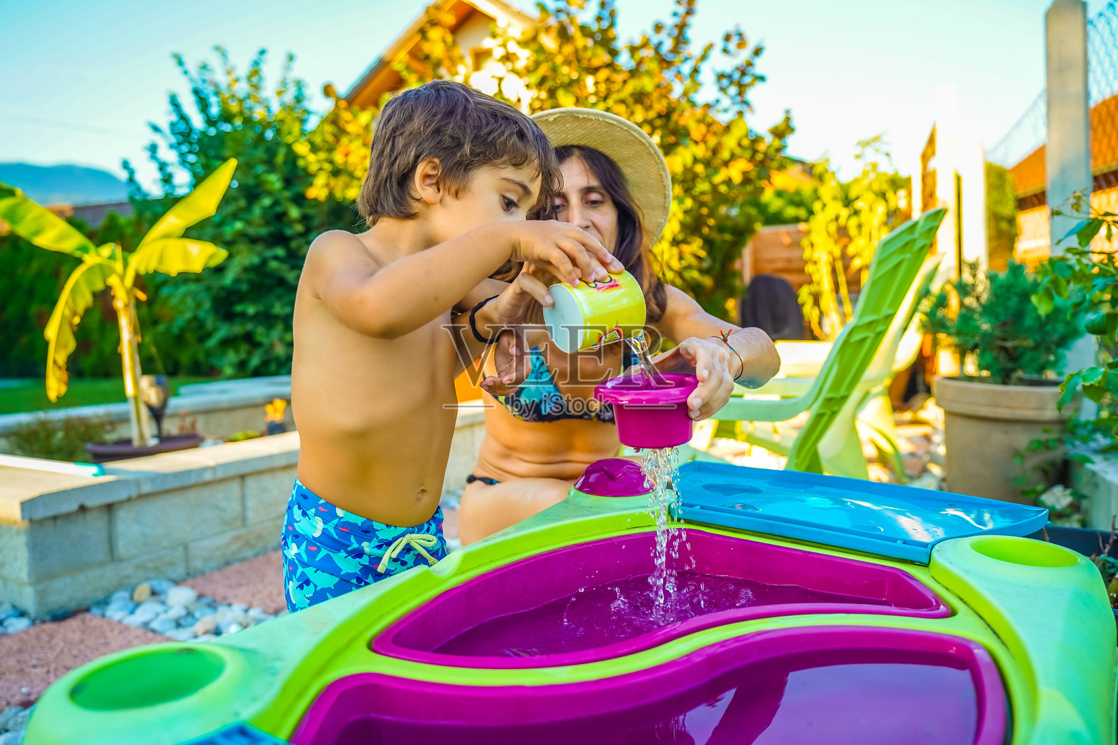 母亲和儿子在花园里玩水桌，享受暑假时光照片摄影图片