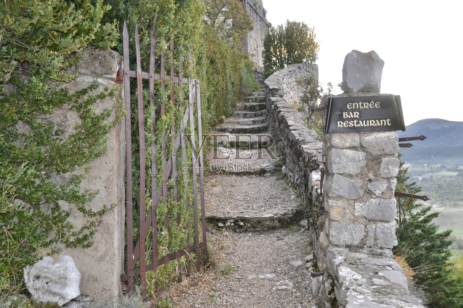 普罗旺斯特里甘斯的山顶石阶和一扇开着的门，旁边有指向餐厅和酒店的标志照片摄影图片