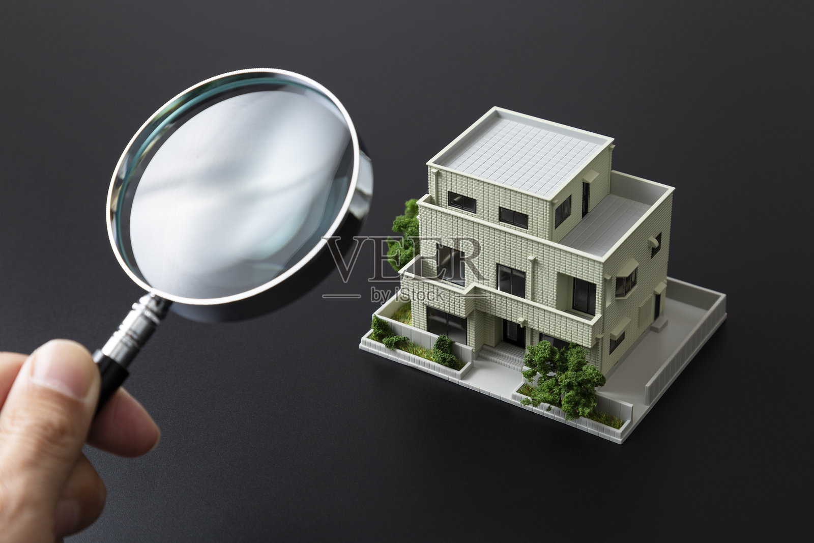 黑色背景上的模型房屋和放大镜。照片摄影图片