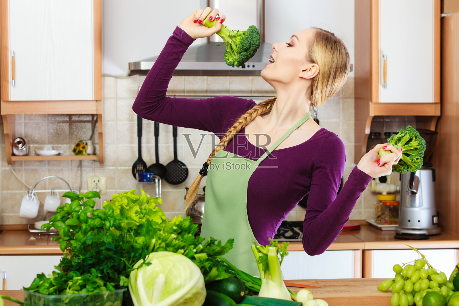 女人在厨房里手里拿着绿色蔬菜西兰花照片摄影图片