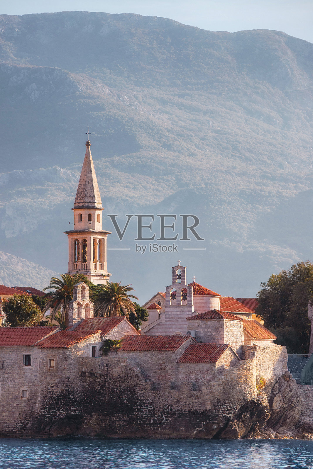 布德瓦老城的红瓦屋顶、古老教堂和防御墙在亚得里亚海和雄伟山脉的背景下构成的美丽景观照片摄影图片