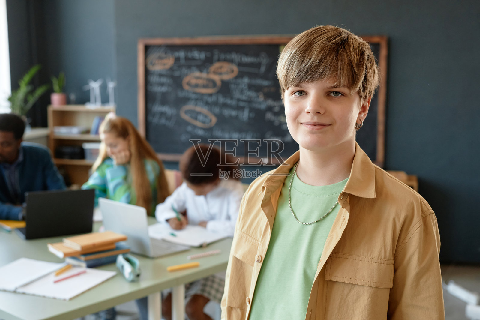 教室里站着的少年男孩，背景是黑板照片摄影图片