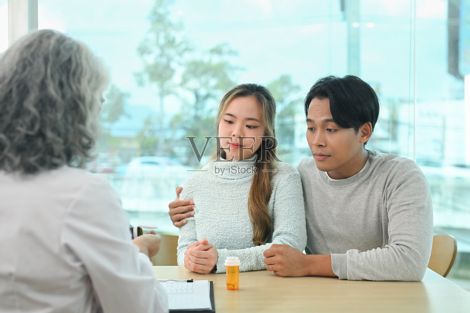 年轻夫妇在咨询期间专心听取资深医生解释治疗方案照片摄影图片