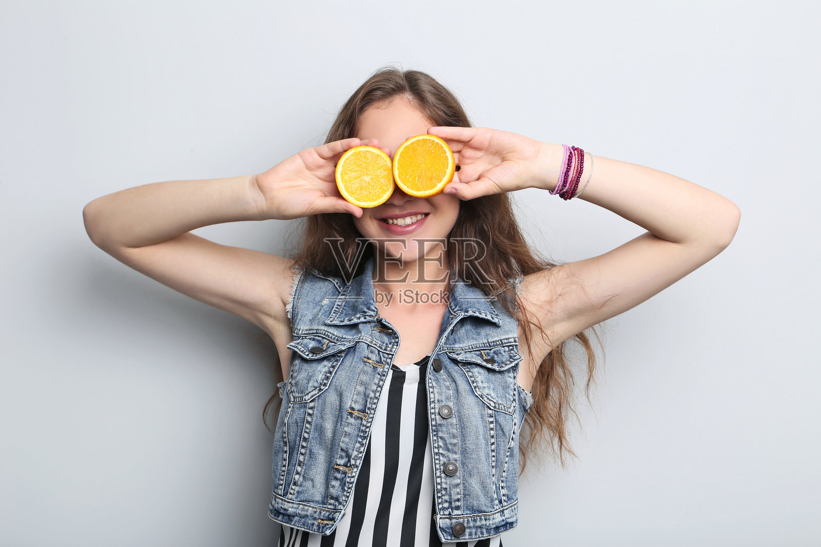 年轻女性与橙色水果的肖像，背景为灰色照片摄影图片