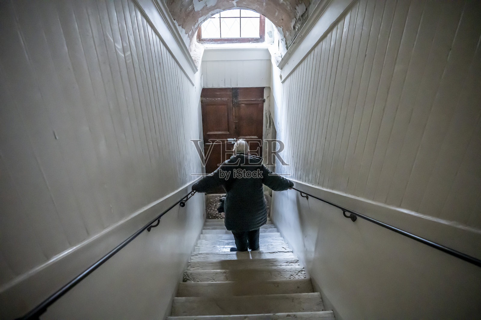 一位年长女士在威尼斯的台阶上小心翼翼地行走。照片摄影图片