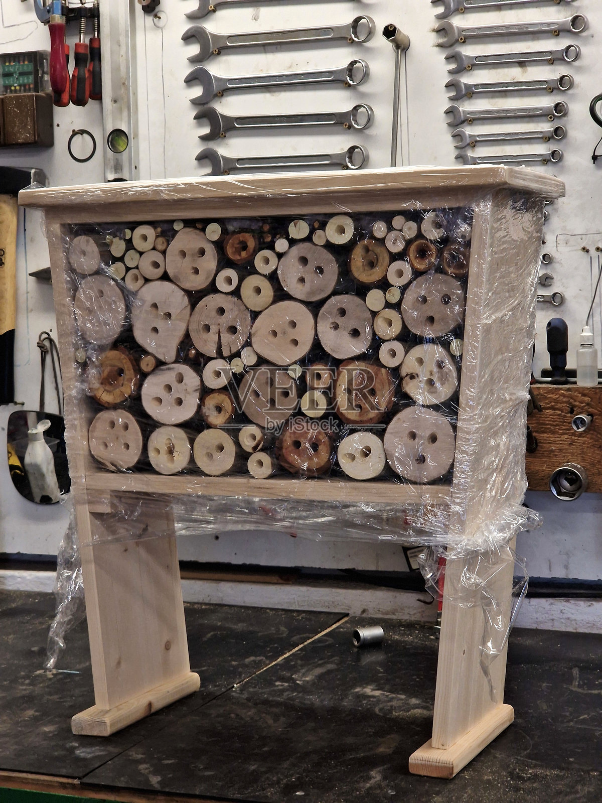 公园草地上的昆虫巢穴。它由多孔的天然材料构成，供昆虫产卵和蛹用。旁边有一个供蜜蜂饮水的水坑，形状像一个盘子。照片摄影图片