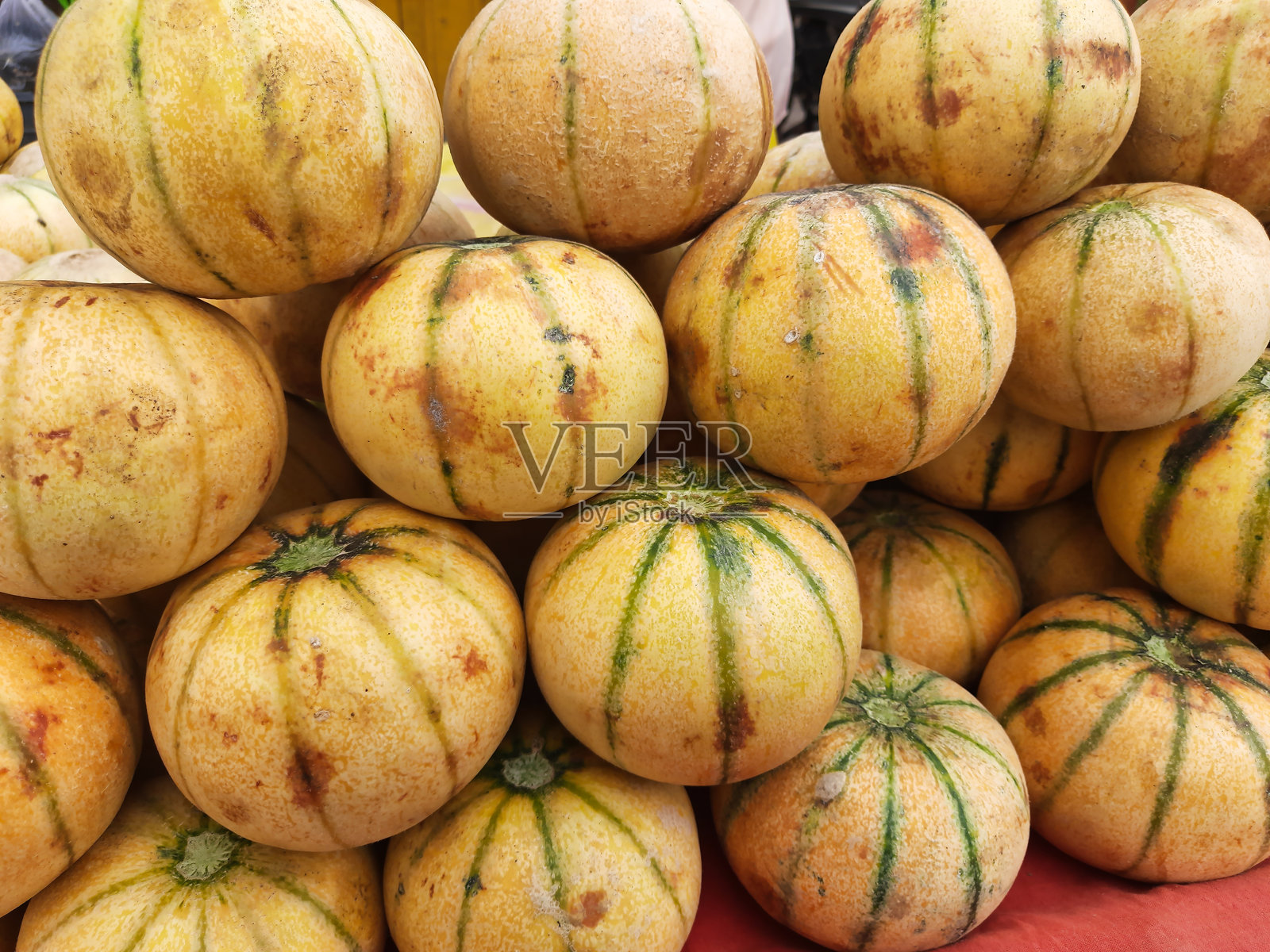 明亮的黄色瓜果上带有绿色条纹，摆满市场展台，吸引顾客享受新鲜的夏季农产品和时令风味。照片摄影图片