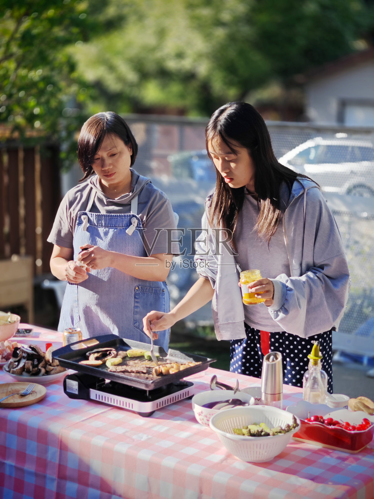 亚洲母亲和青少女在后院享受烧烤和户外烹饪照片摄影图片
