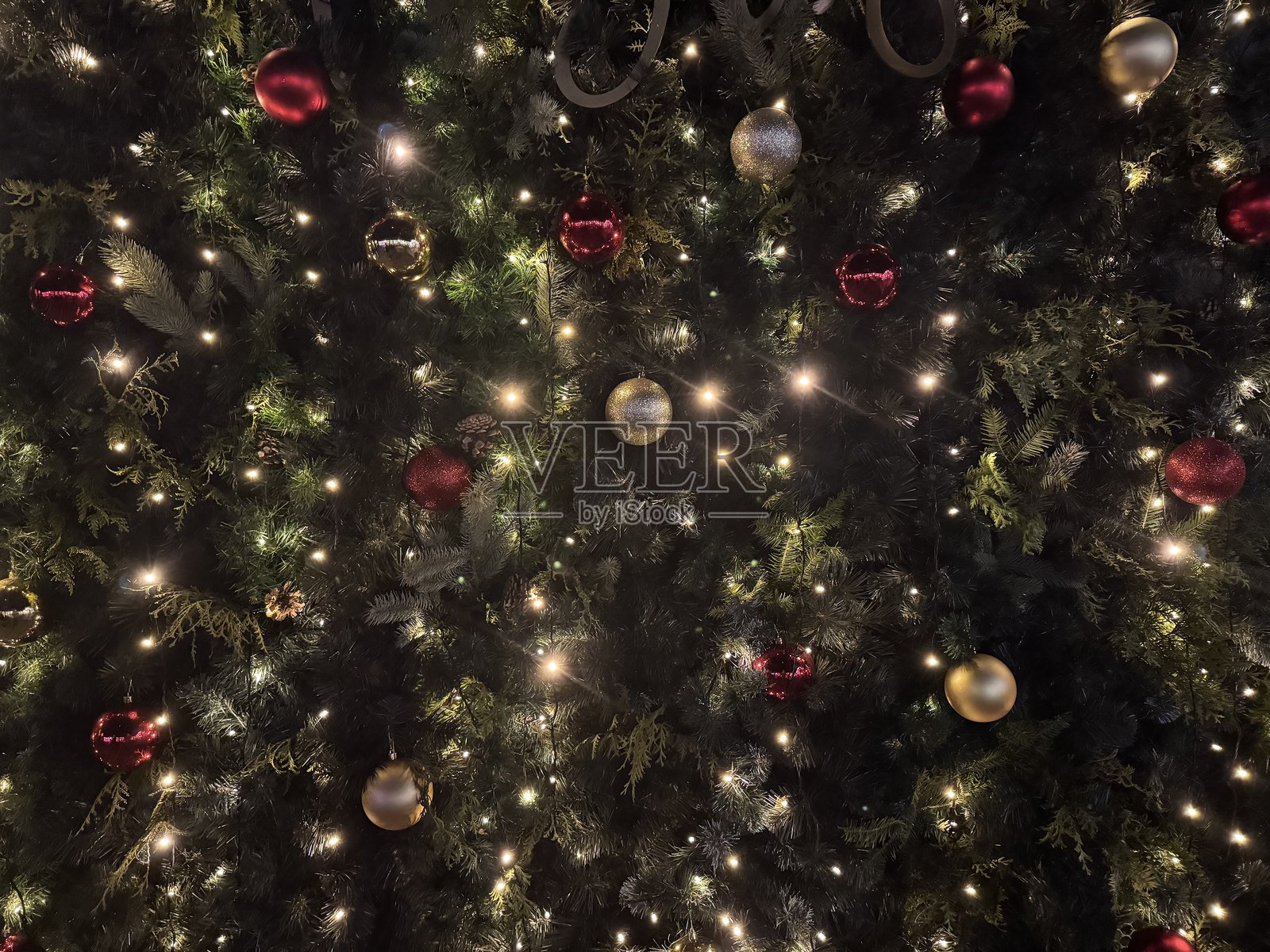 绿色圣诞树枝的背景上装饰着圆形的新年球。新年装饰和灯饰的布置。照片摄影图片