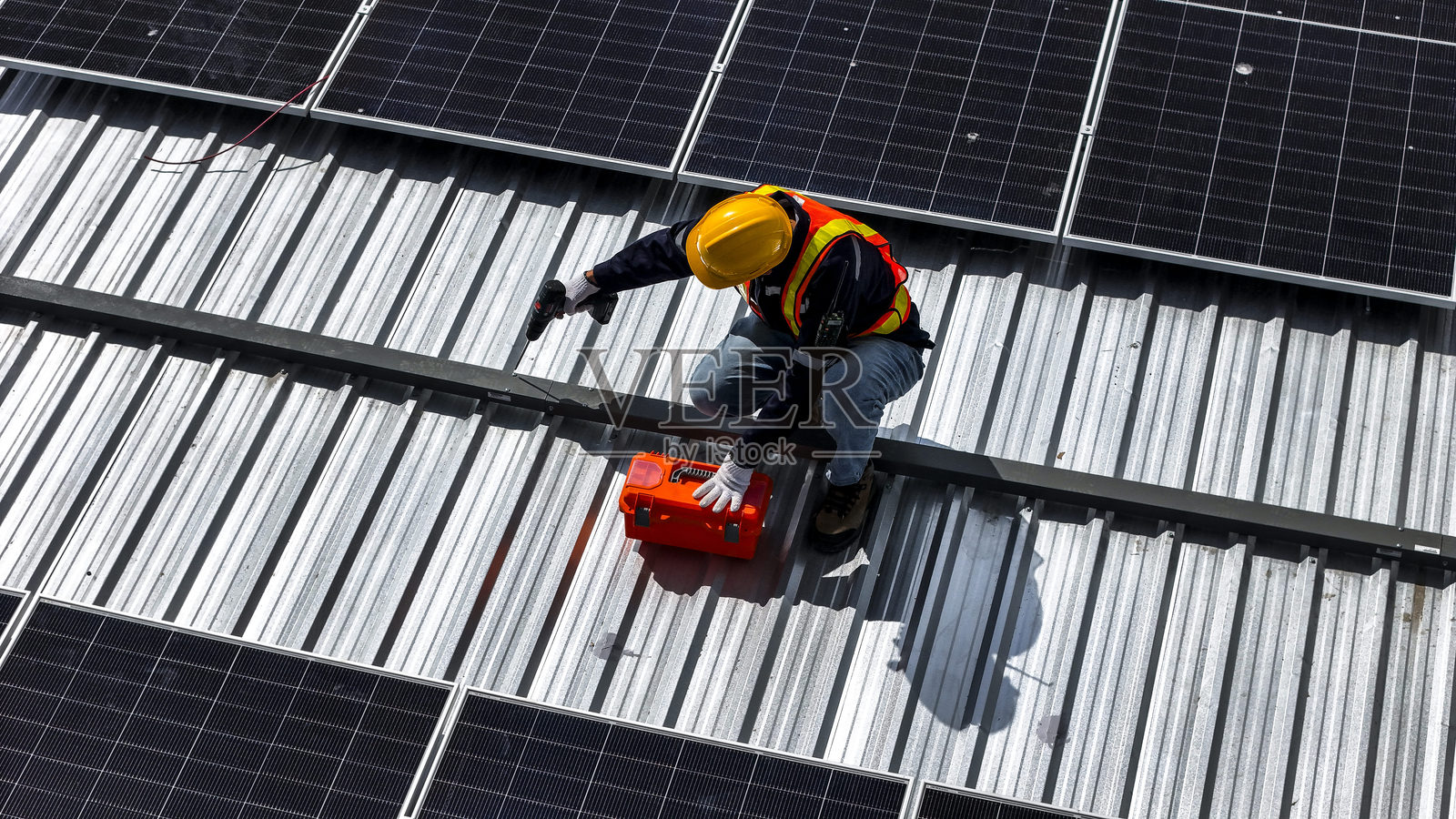 工人在阳光明媚的环境中安装和检查屋顶上的太阳能电池板，突显可再生能源、可持续性以及现代技术在太阳能系统中的高效利用。照片摄影图片