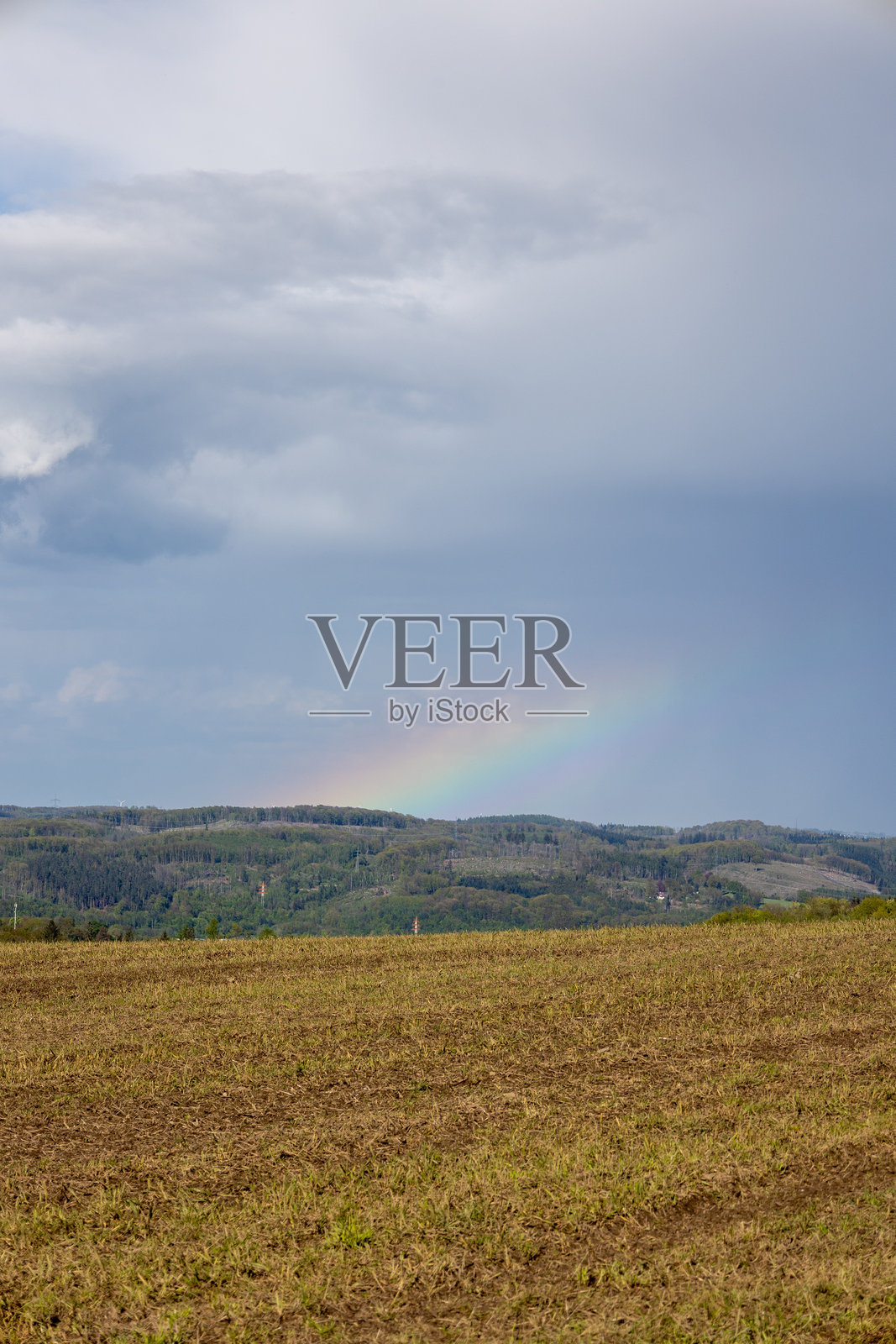 天空中出现了一道彩虹，映衬着田野。照片摄影图片