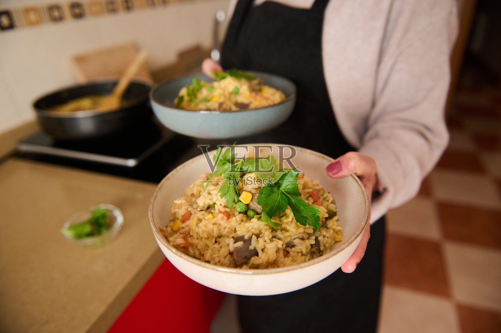 厨师在温馨的厨房环境中端着几碗西班牙海鲜饭照片摄影图片