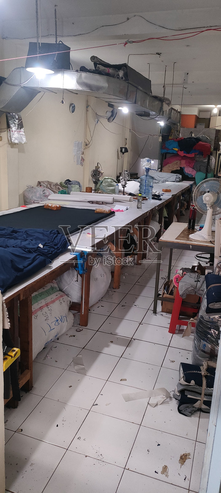 纺织车间内有长切割台、布料卷和工业缝纫设备照片摄影图片