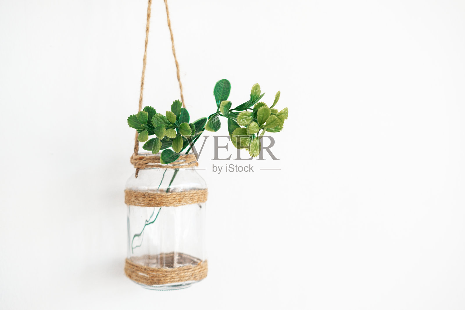 悬挂的玻璃罐，缠绕麻绳和绿色植物，挂在白色墙壁上照片摄影图片
