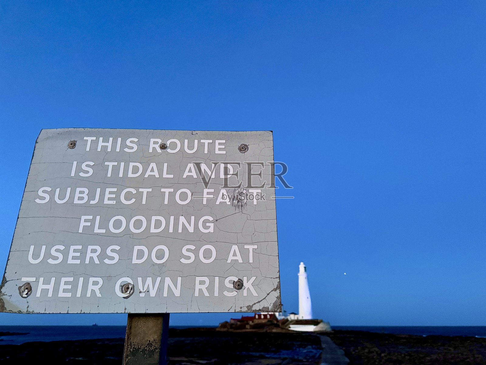 泰恩和威尔地区圣玛丽岛堤道上的潮汐警告标志照片摄影图片