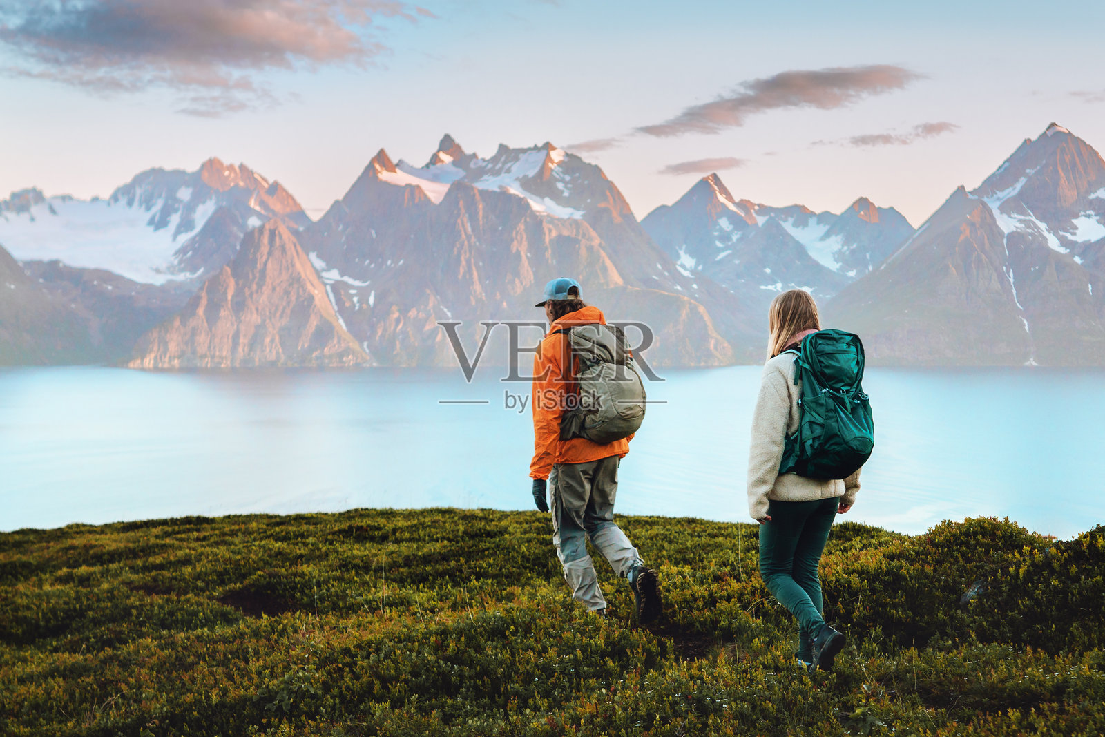 在挪威徒步旅行的情侣，男士和女士背着背包，享受健康的户外活动，家庭攀登林根阿尔卑斯山，冒险、自由和耐力的概念照片摄影图片