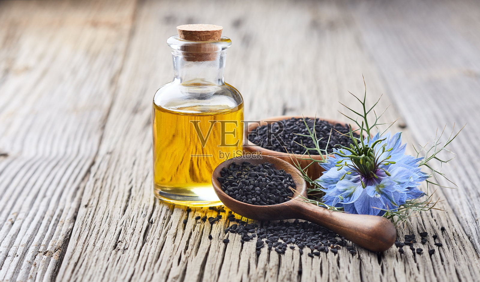 黑种草种子与黑种草花在古老的木质背景上照片摄影图片