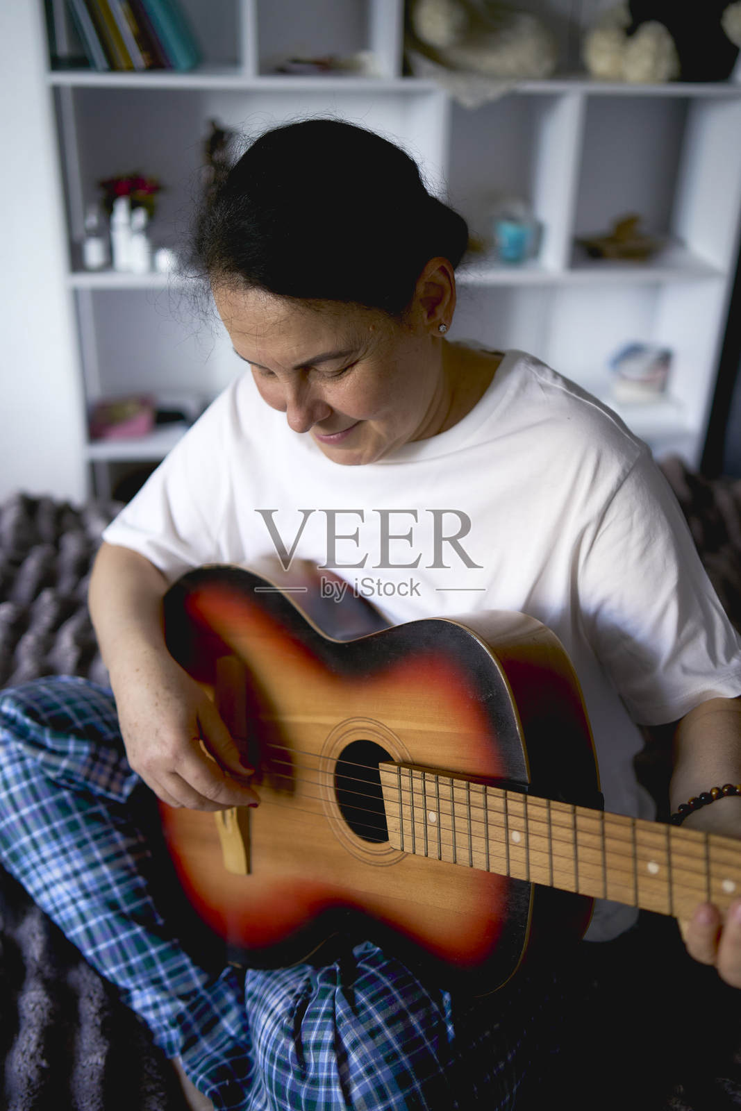 一位年长女性通过在线课程学习弹吉他照片摄影图片