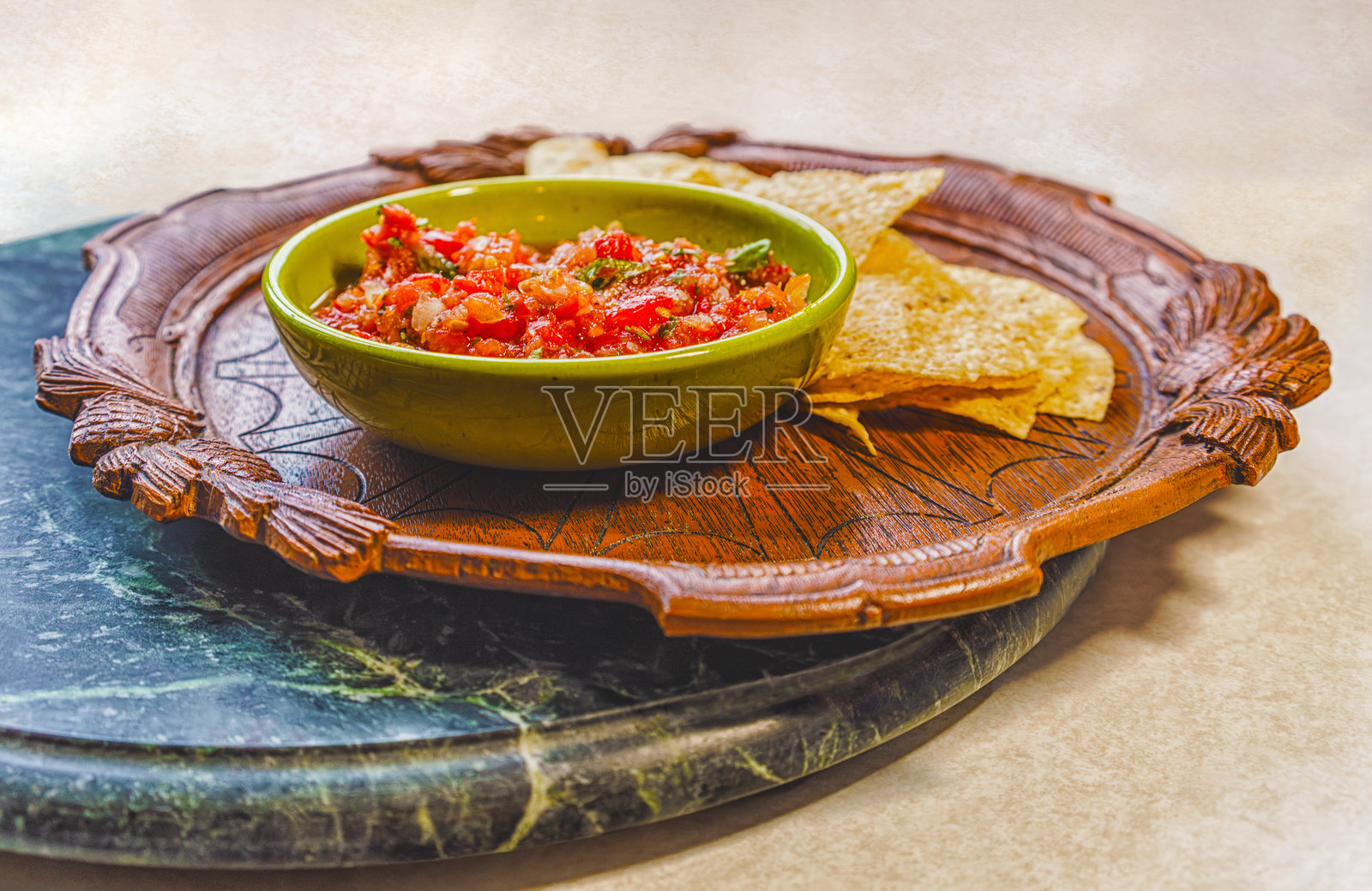 新鲜有机莎莎酱放在复古碗中，玉米片则放在古董木盘上，置于大理石托盘上。照片摄影图片