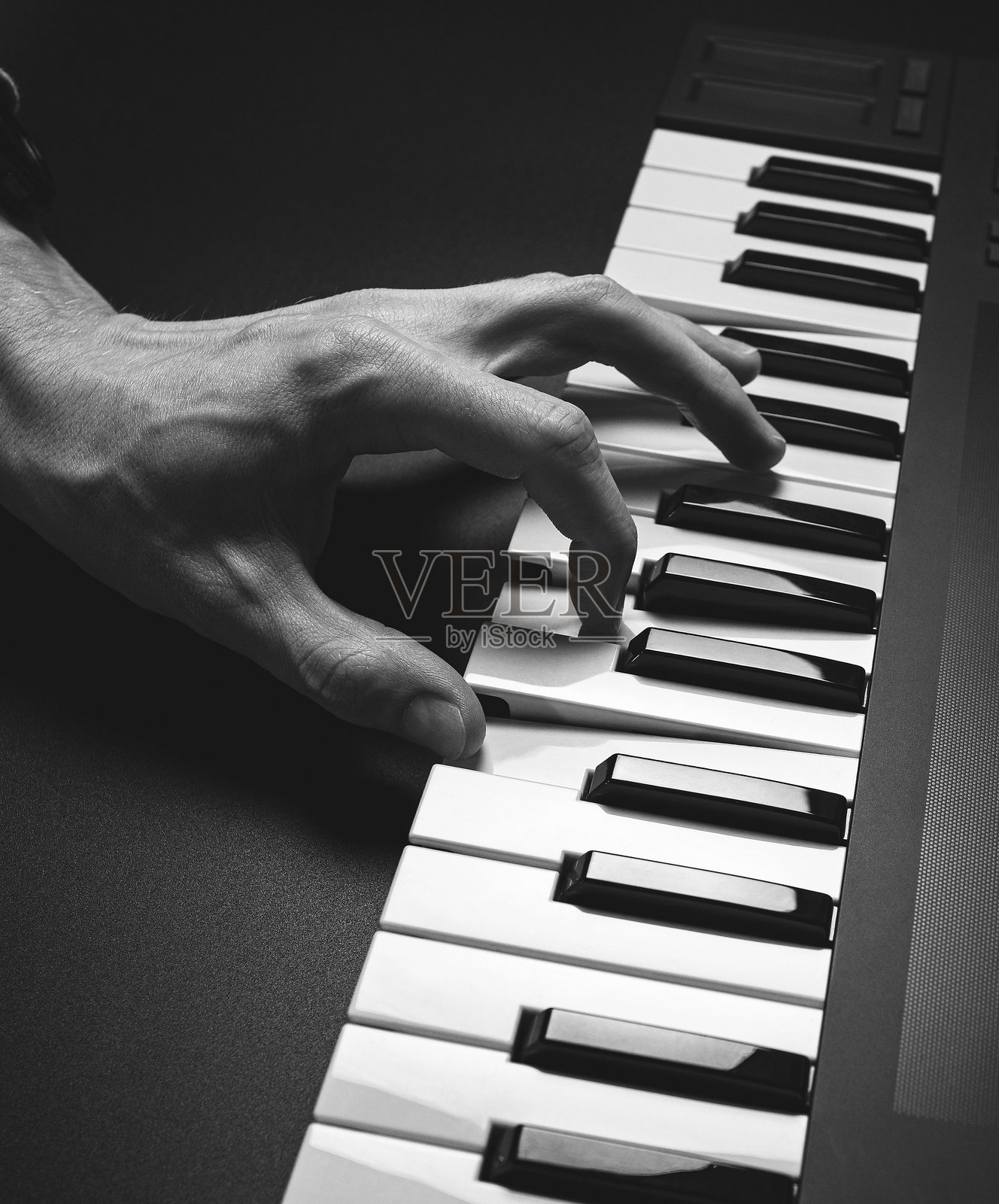 一个男人的手在演奏的MIDI键盘，钢琴键。照片摄影图片