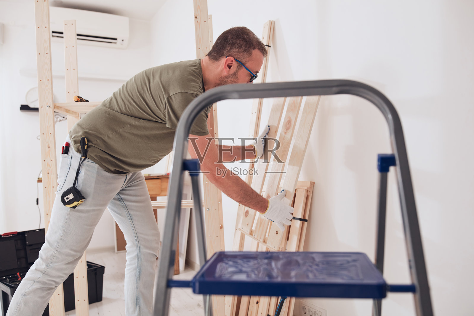 男子在公寓里组装新的木制书架和家具。照片摄影图片