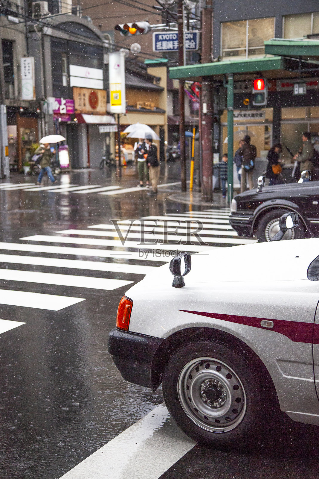 京都祇园的四条通在雨中,前景是一辆白色出租车。照片摄影图片