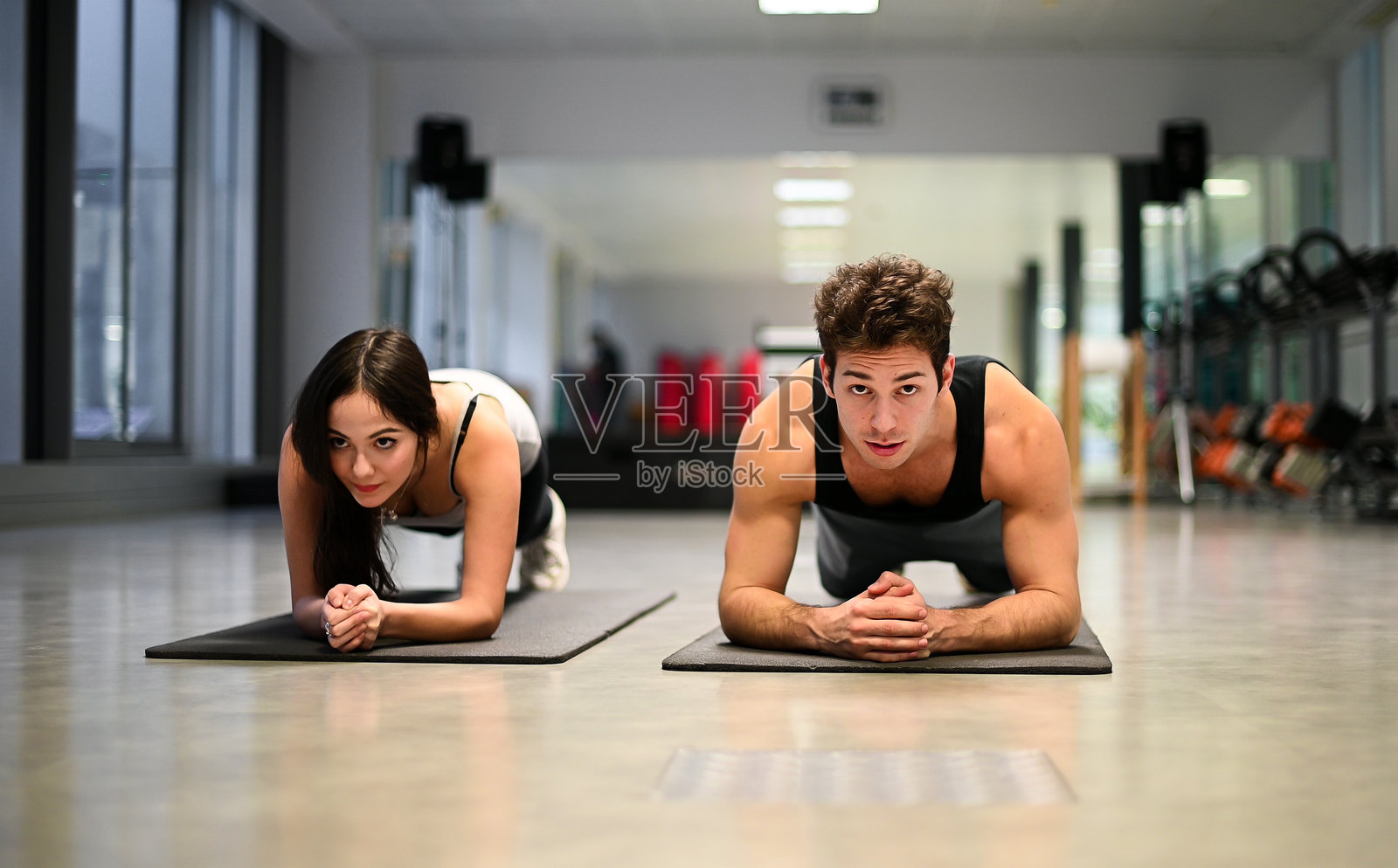 年轻情侣在健身房做平板支撑练习照片摄影图片
