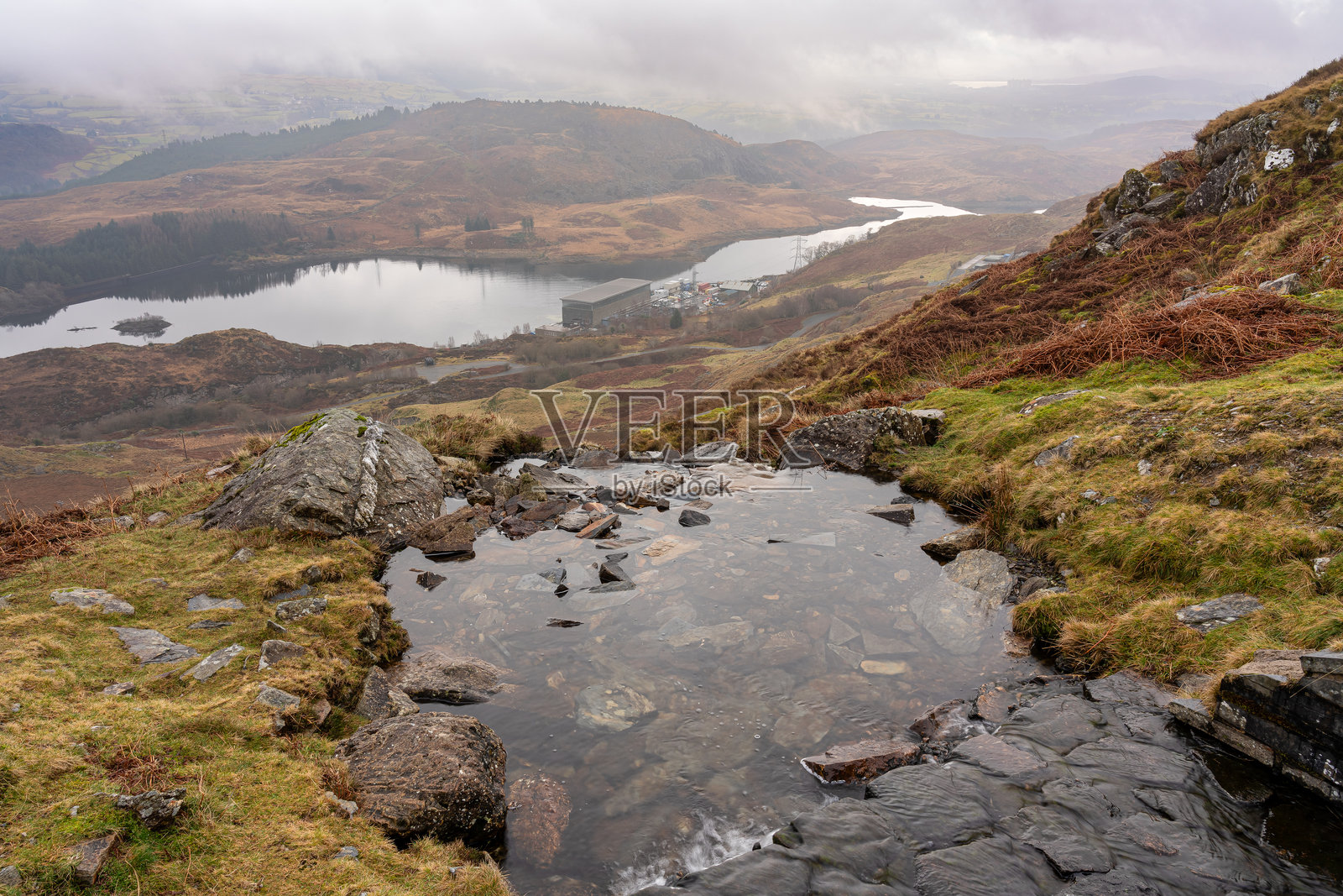 水流从山上流向位于威尔士格温内德的坦格里斯山谷的Ffestiniog水电站，湖泊为Tanygrisiau，位于斯诺多尼亚国家公园内。照片摄影图片
