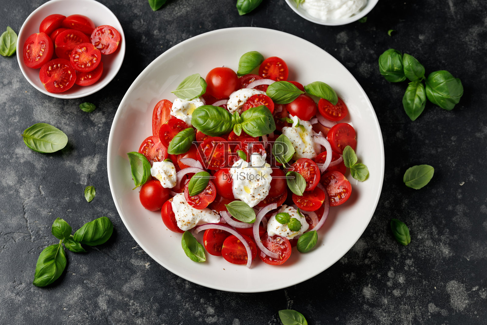 意大利乳清干酪沙拉配樱桃番茄、洋葱和罗勒。健康食品照片摄影图片