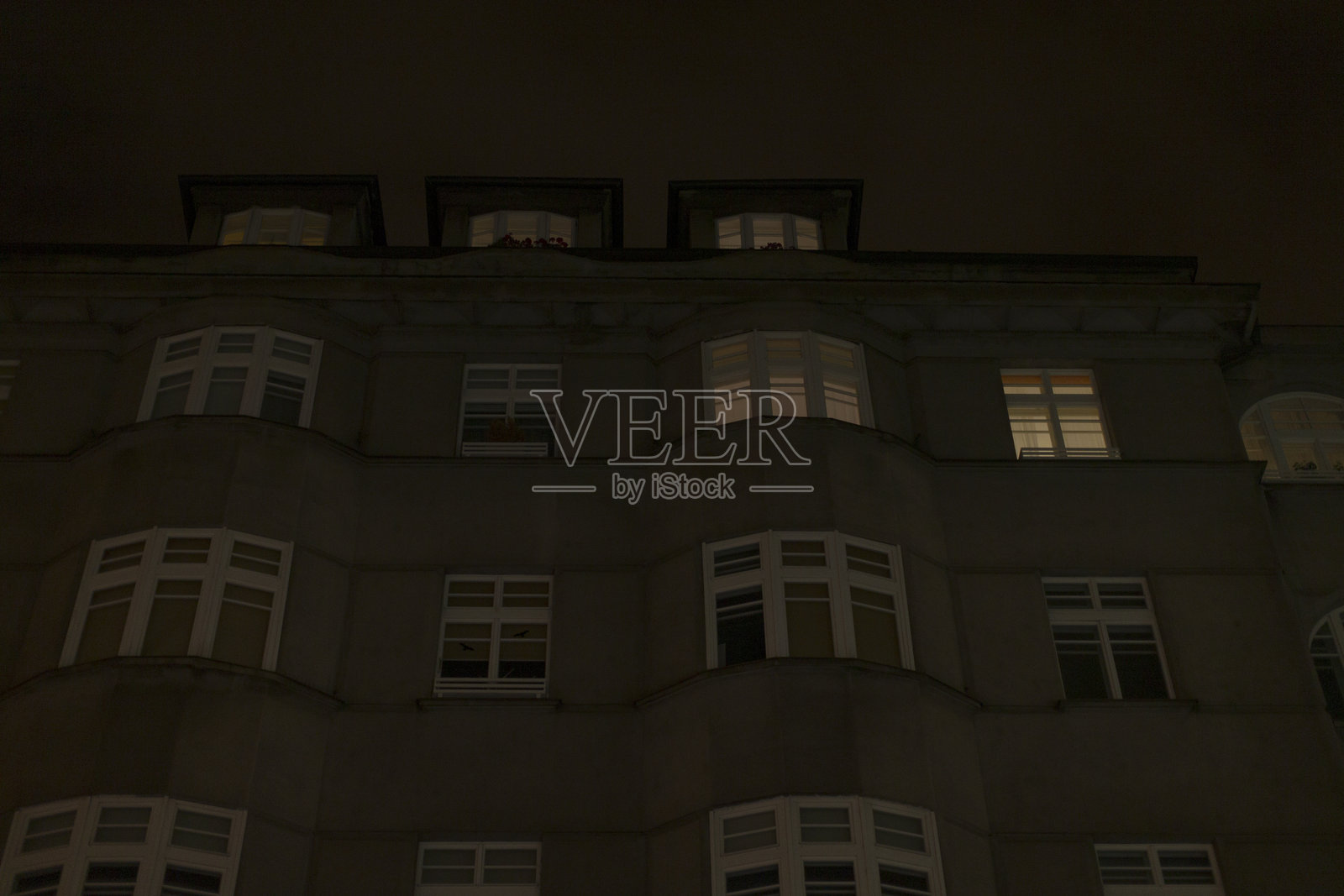 令人惊叹的公寓楼夜景，展示了亮灯的窗户照片摄影图片