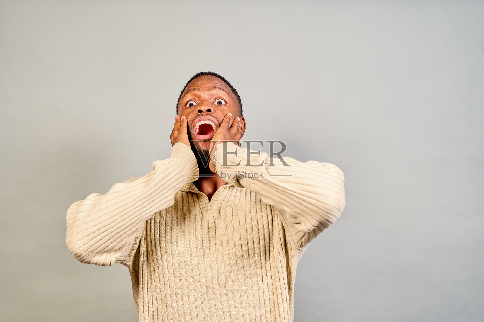 震惊的年轻人捂着脸，表达惊讶和震撼。照片摄影图片