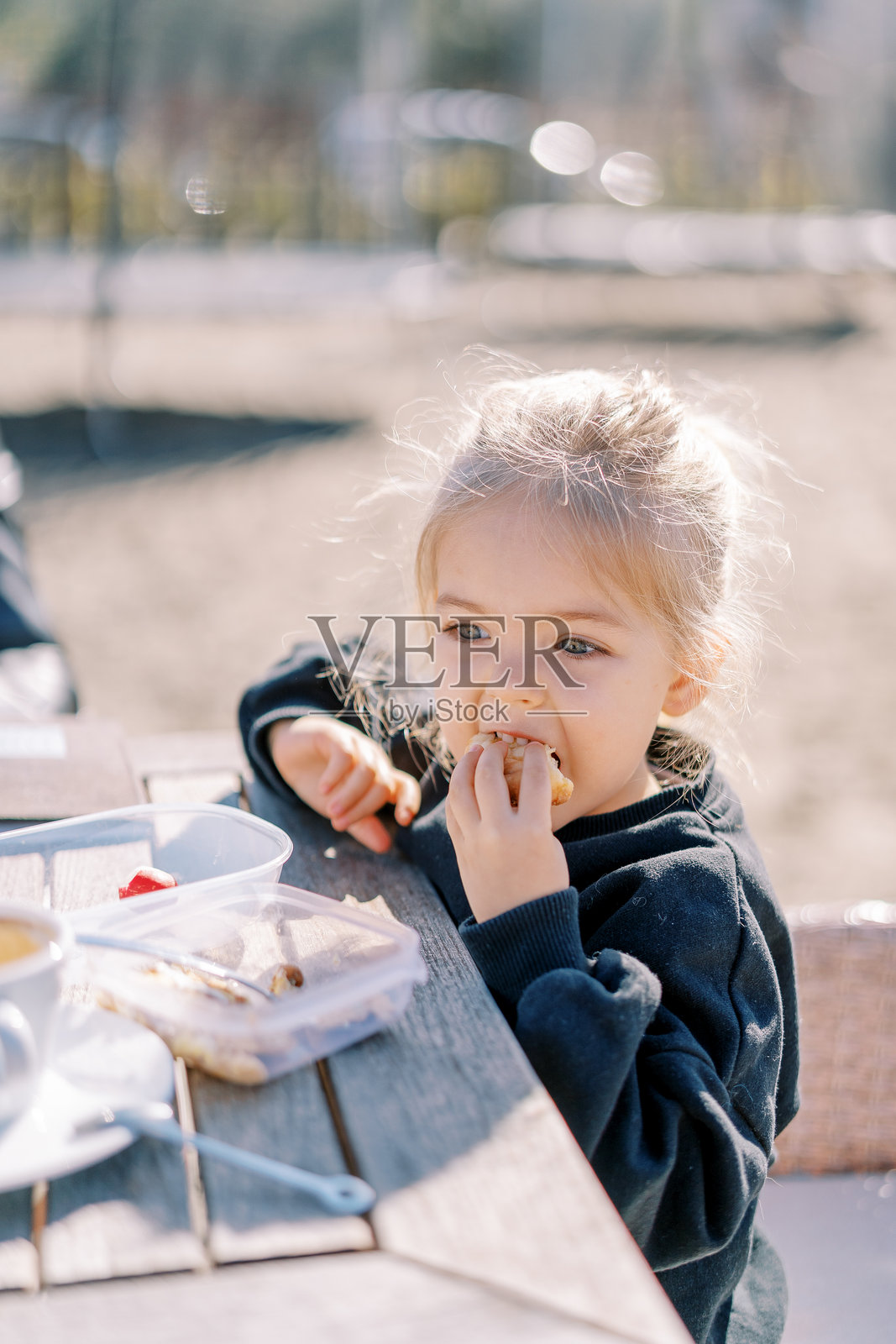 小女孩坐在公园的木桌旁吃煎饼照片摄影图片