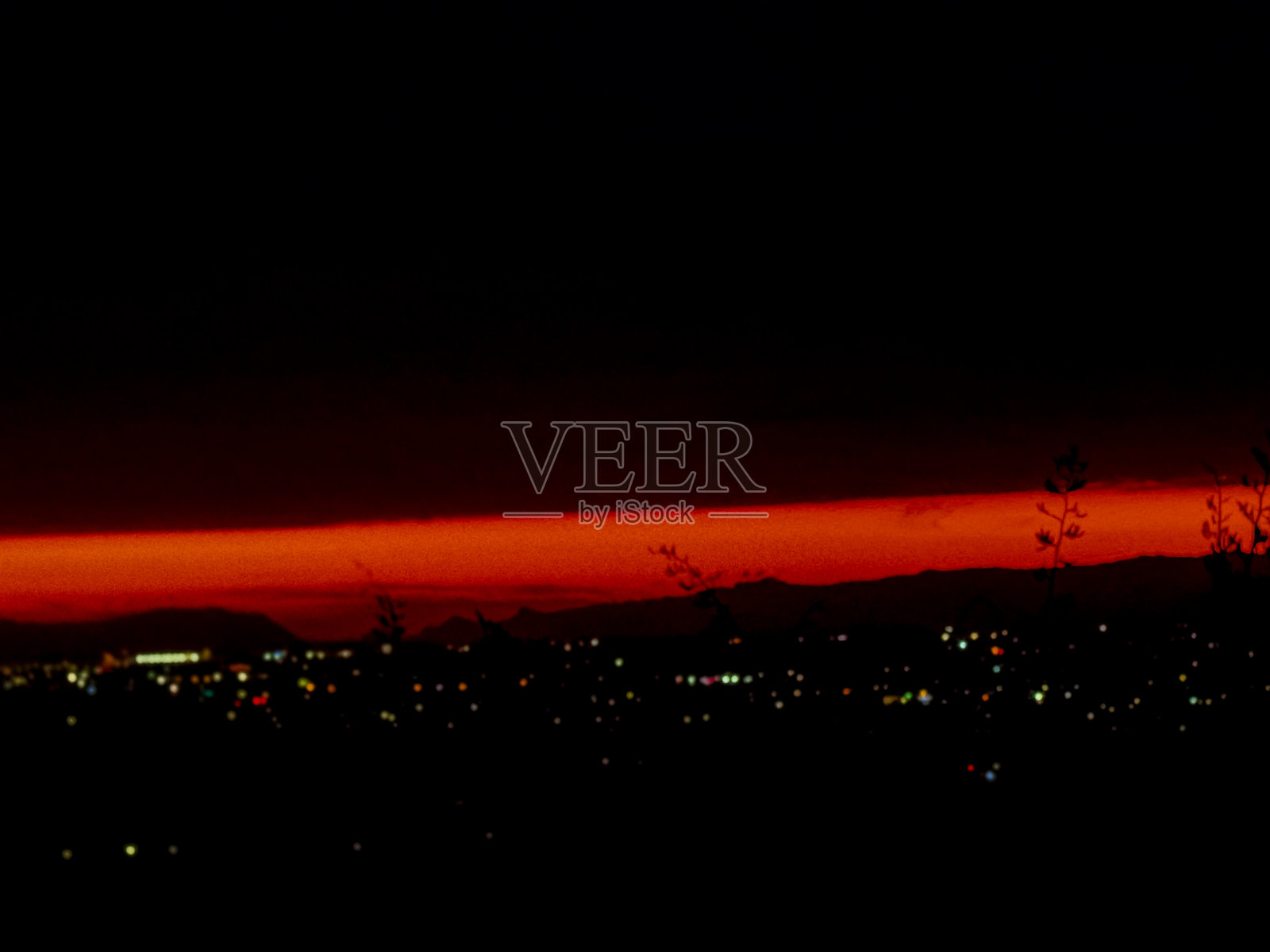 太阳正缓缓落在山丘和海洋的地平线上。照片摄影图片