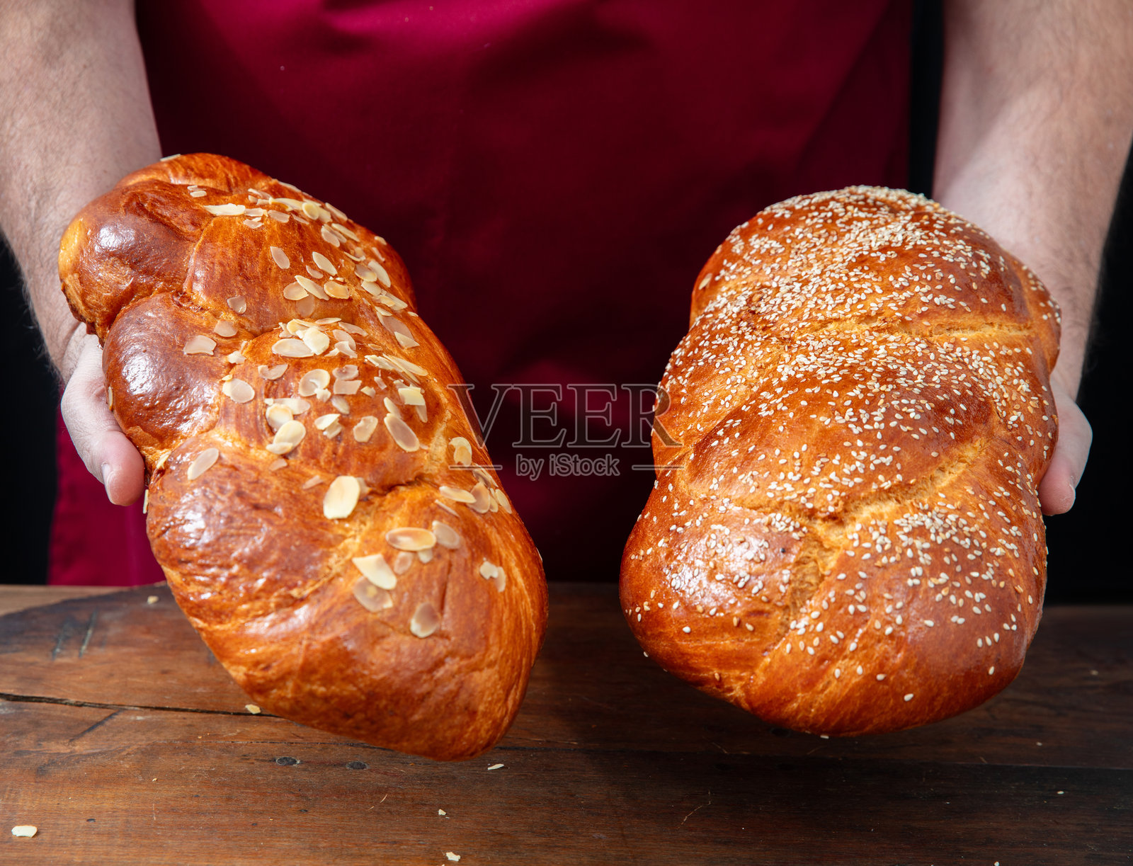 复活节甜面包，面包师的手握着两条新鲜出炉的茴香面包辫子，放在木桌上照片摄影图片
