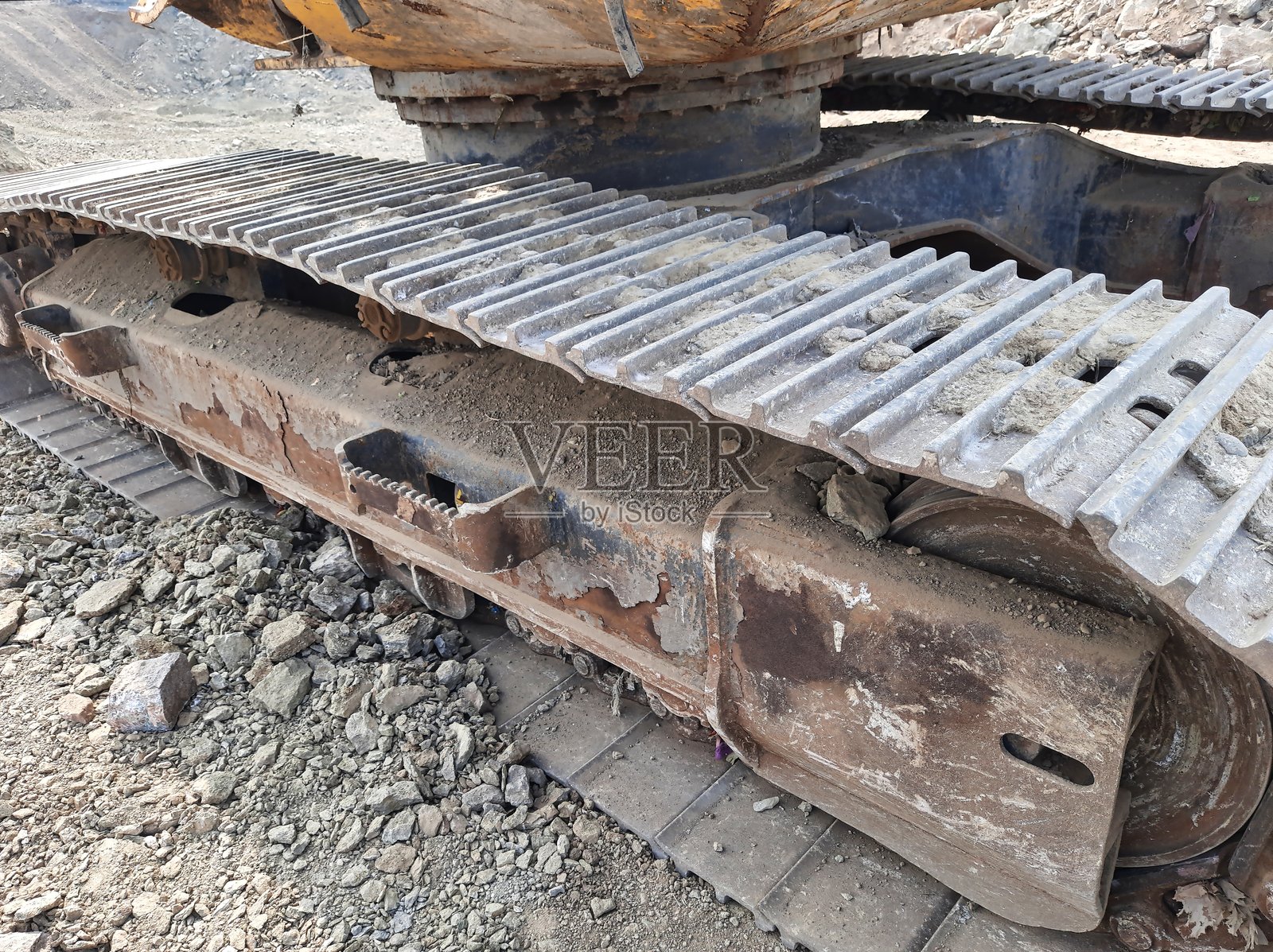 重型设备履带的特写，显示出磨损的迹象。尘土和碎石环绕着建筑工地上的机械。照片摄影图片