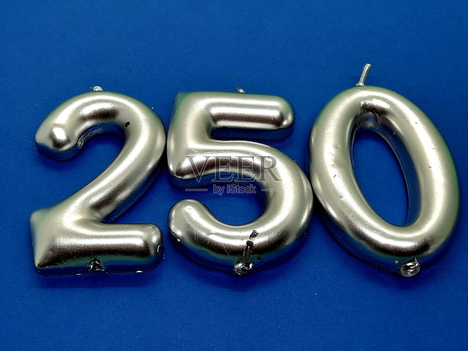 蓝色背景上的250号生日蜡烛。照片摄影图片