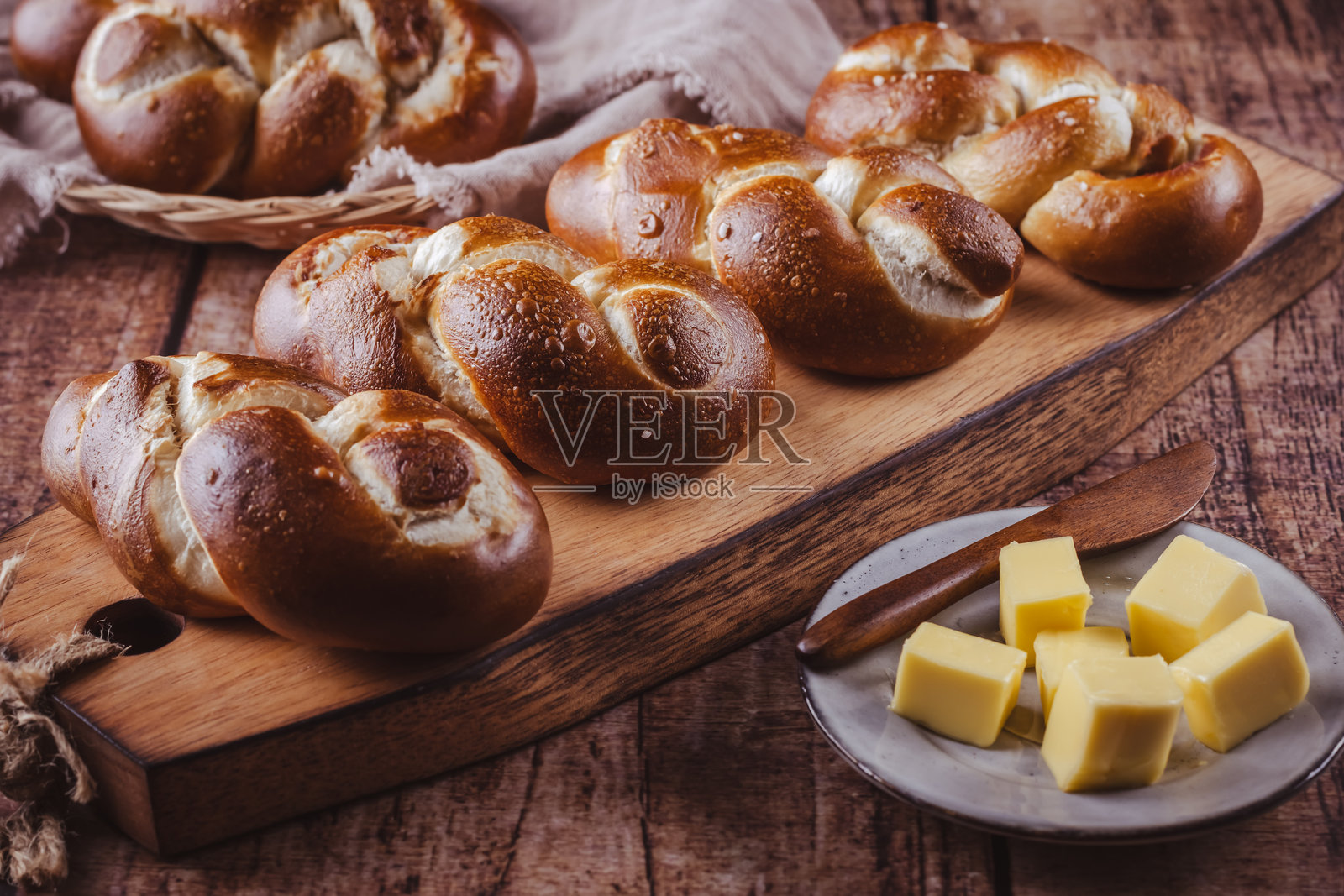 黄油和盐的椒盐卷饼卷或小圆面包放在木砧板上照片摄影图片