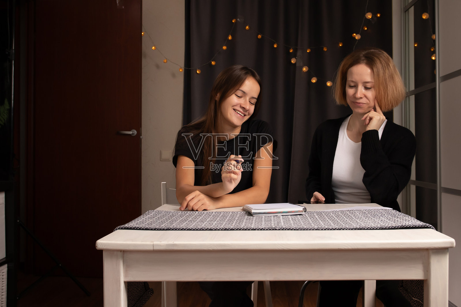 母女一起在笔记本上写作，家庭时光与教育，指导和引导青少女照片摄影图片