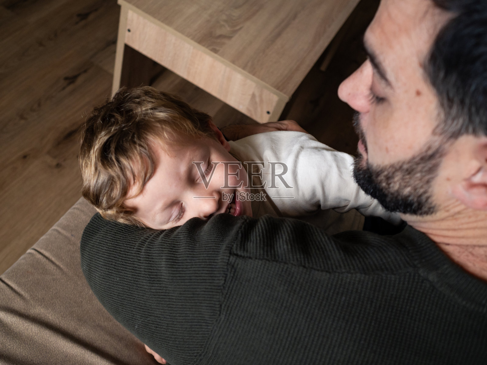 男人在家中傍晚时分温暖地拥抱着孩子照片摄影图片