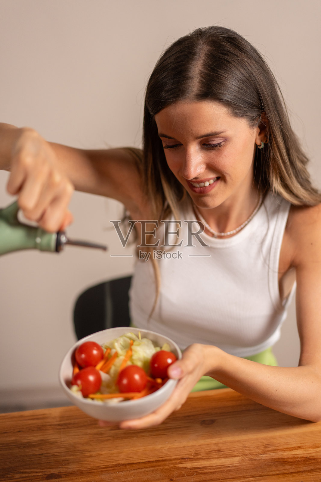 年轻女性微笑着享用健康沙拉碗，里面有新鲜蔬菜，体现饮食生活方式，番茄，健康营养。照片摄影图片