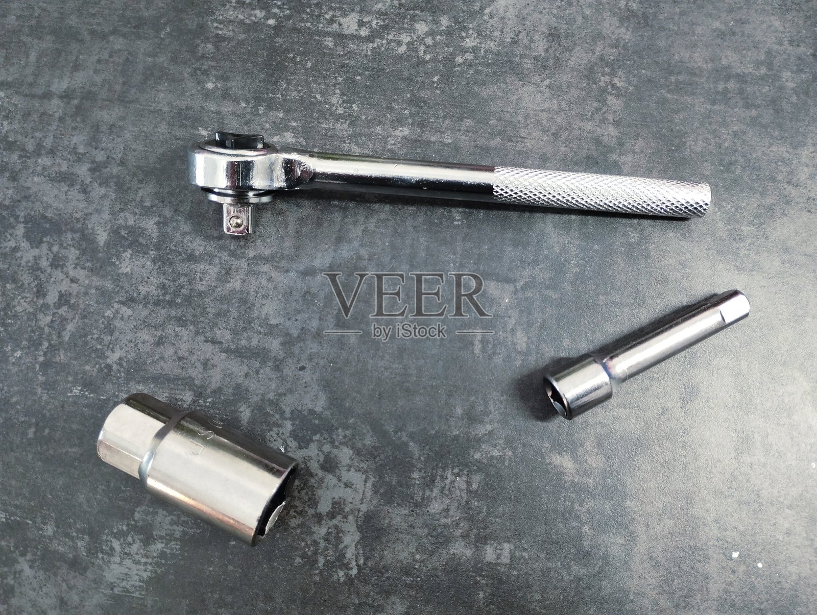 金属扳手头和金属延长杆，背景为灰色和深色混凝土结构。维修和工业主题。手动工具。照片摄影图片