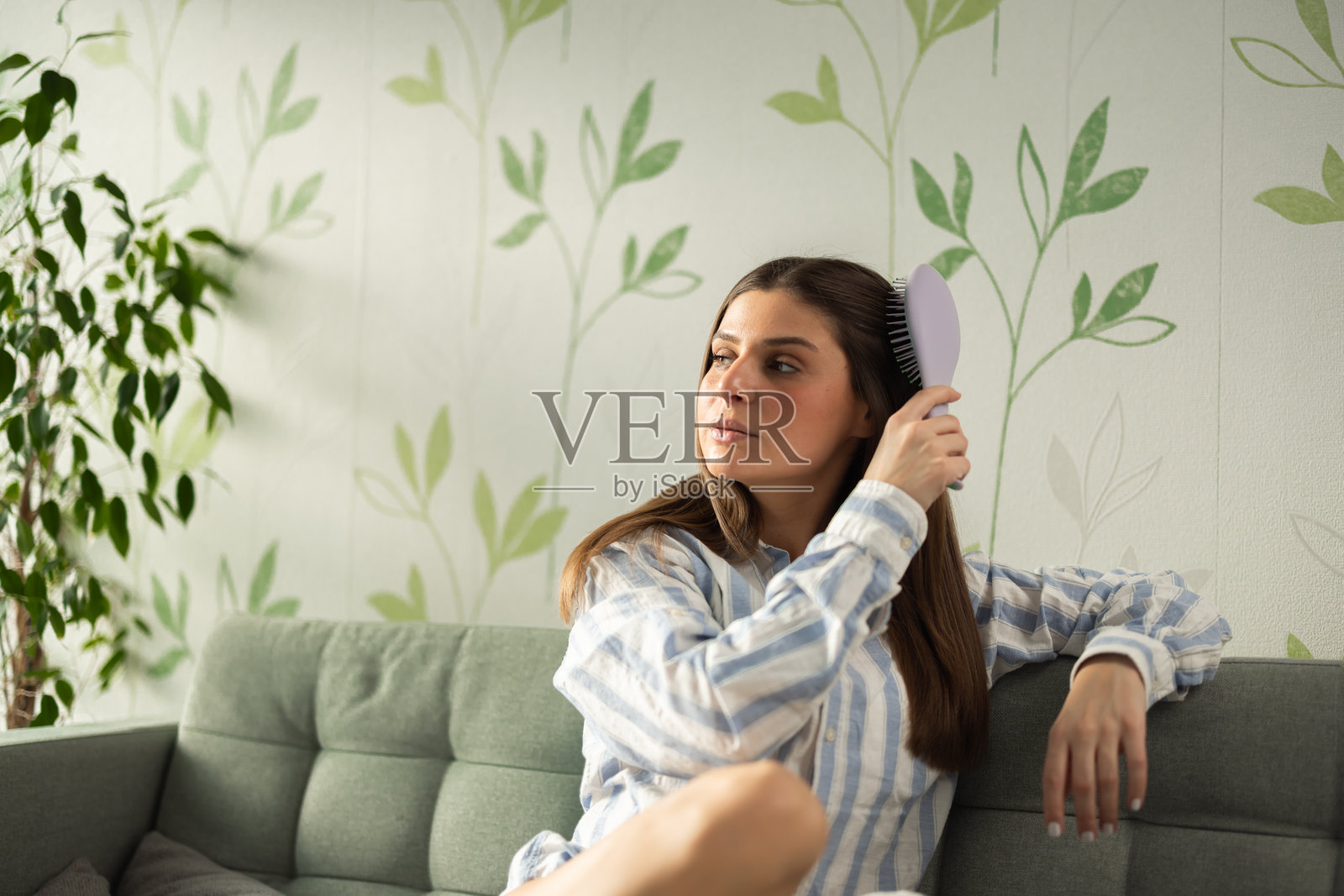 美丽的女孩在沙发上梳头发照片摄影图片